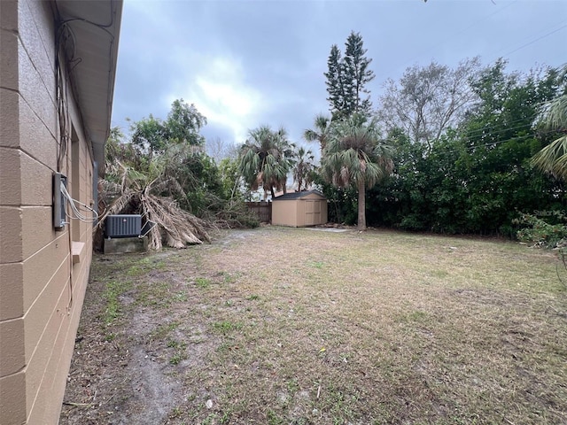 view of yard with a storage shed, an outbuilding, fence, and central air condition unit