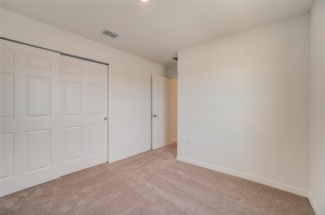 unfurnished bedroom featuring a closet, light carpet, visible vents, and baseboards