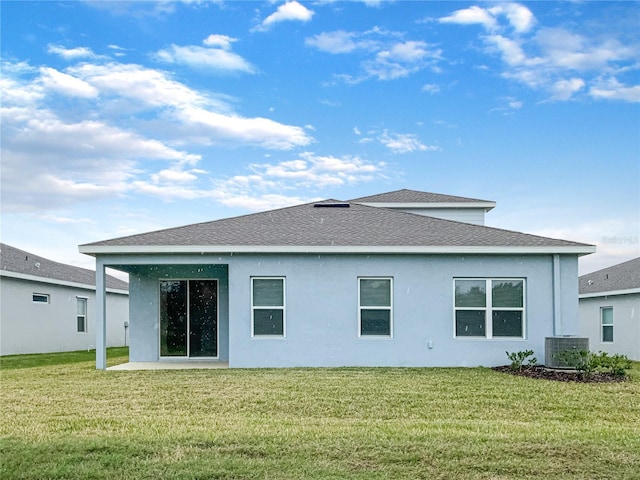 rear view of property featuring stucco siding, a lawn, central AC, and roof with shingles