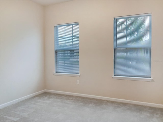 carpeted spare room featuring baseboards