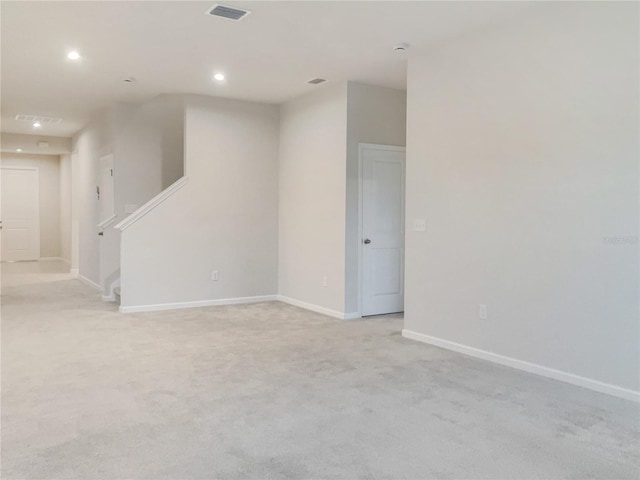 unfurnished room featuring recessed lighting, light carpet, visible vents, baseboards, and stairs