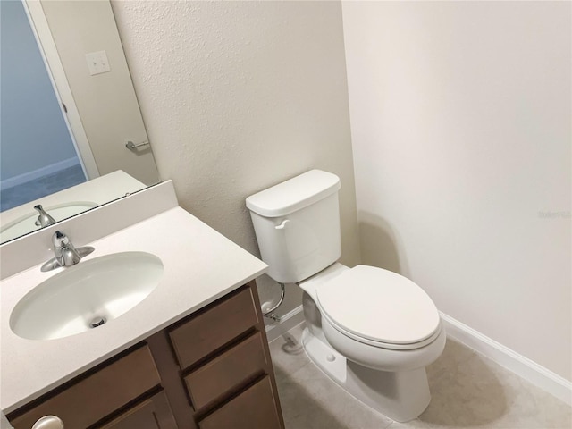 bathroom featuring baseboards, vanity, and toilet