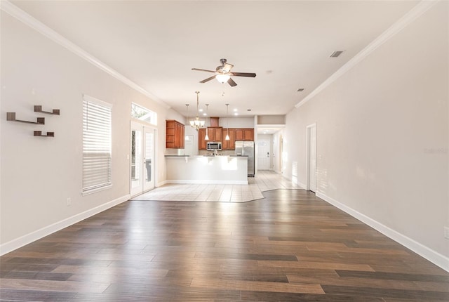 unfurnished living room featuring ceiling fan with notable chandelier, visible vents, crown molding, and wood finished floors