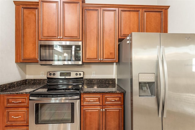 kitchen featuring dark stone counters, appliances with stainless steel finishes, and brown cabinets