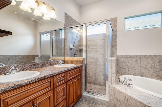 full bath with a bath, tile patterned flooring, a shower stall, and a sink