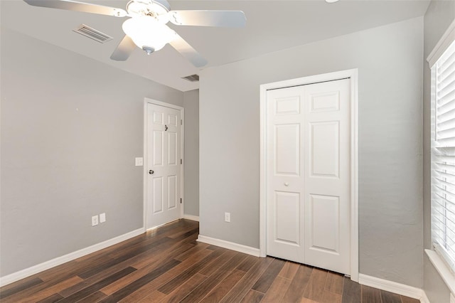 unfurnished bedroom featuring dark wood-style flooring, visible vents, and baseboards