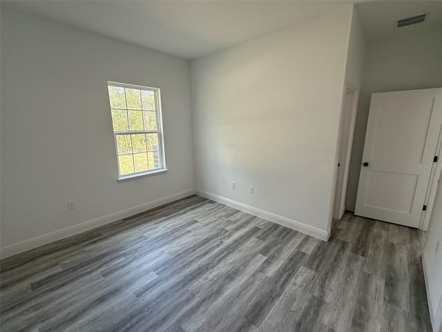 spare room with visible vents, baseboards, and wood finished floors