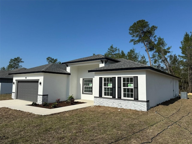 prairie-style home featuring an attached garage, stone siding, concrete driveway, and stucco siding