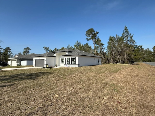 view of front of home with an attached garage, a front lawn, concrete driveway, and stucco siding