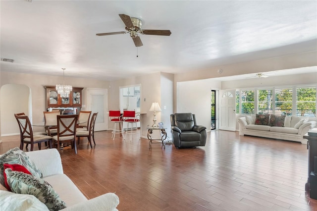 living area featuring visible vents, dark wood finished floors, and ceiling fan with notable chandelier