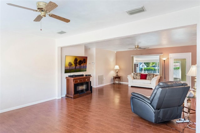 living area with wood finished floors, visible vents, and baseboards