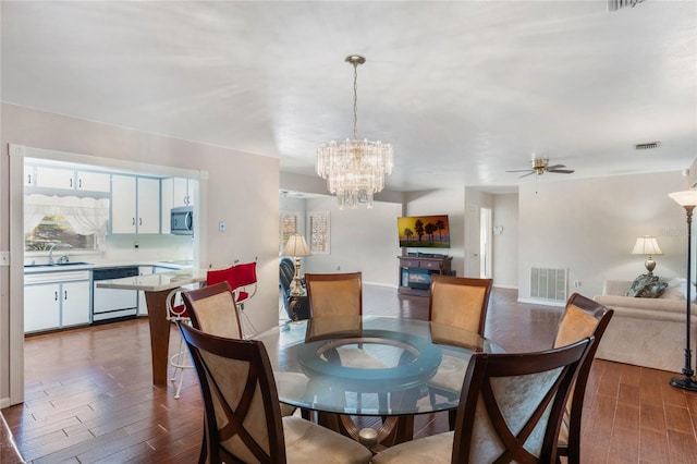 dining area featuring ceiling fan with notable chandelier, dark wood-type flooring, and visible vents