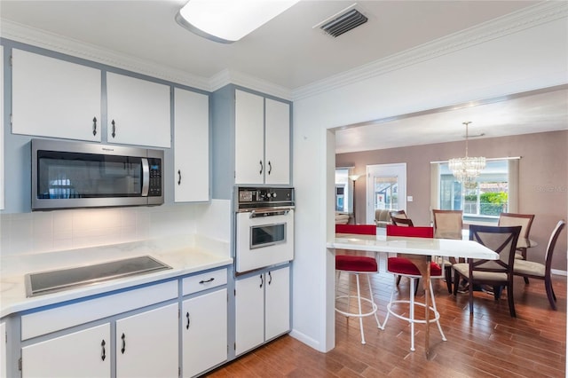 kitchen with visible vents, stainless steel microwave, oven, hanging light fixtures, and light countertops