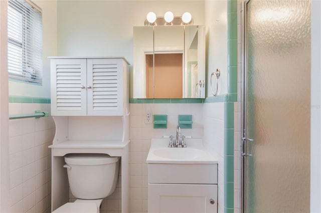 bathroom with a wainscoted wall, tile walls, toilet, an enclosed shower, and vanity