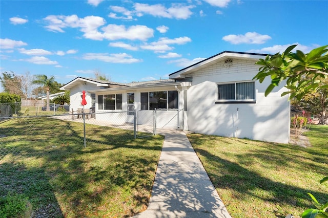 view of front of property with concrete block siding, a front yard, fence private yard, and a gate