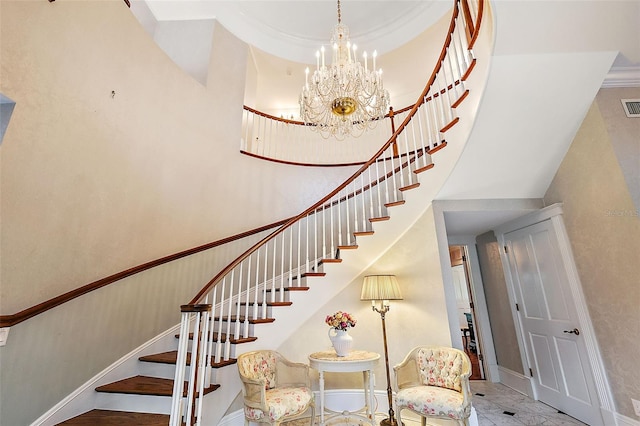 staircase with visible vents, baseboards, a towering ceiling, and a notable chandelier