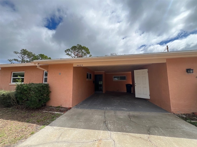 view of side of property featuring a carport, driveway, and stucco siding