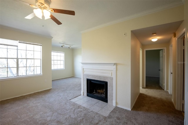 unfurnished living room with a tile fireplace, carpet floors, baseboards, ornamental molding, and track lighting