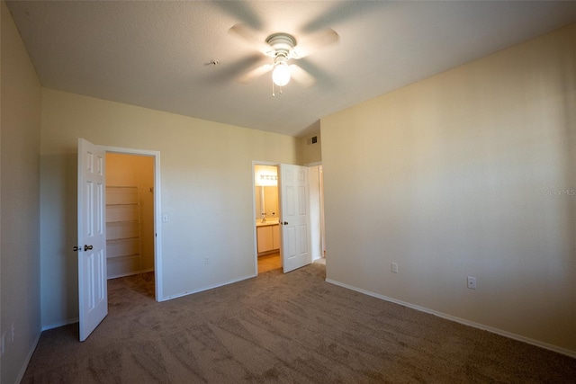 unfurnished bedroom featuring baseboards, visible vents, connected bathroom, carpet, and a walk in closet