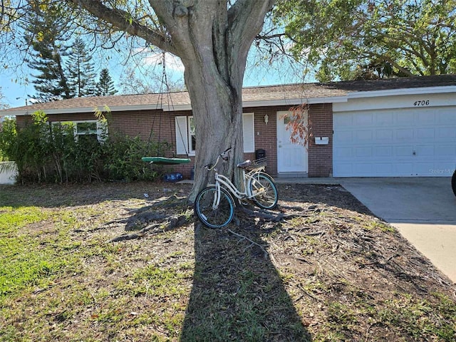 single story home with an attached garage, concrete driveway, and brick siding