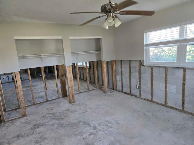 empty room with unfinished concrete floors and a ceiling fan