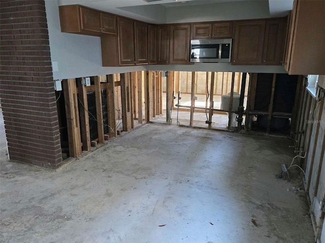 kitchen featuring stainless steel microwave and unfinished concrete flooring