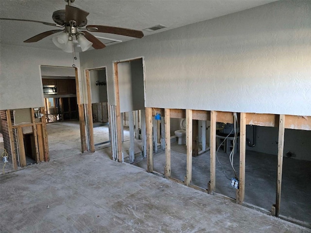 spare room featuring a ceiling fan, visible vents, and unfinished concrete flooring