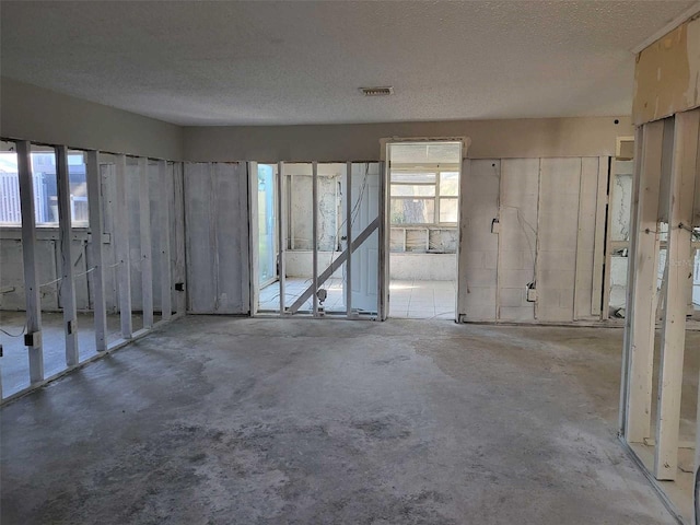 misc room with unfinished concrete floors, visible vents, and a textured ceiling