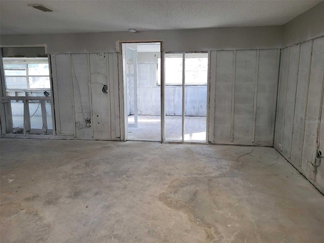 empty room featuring visible vents, unfinished concrete flooring, and a textured ceiling