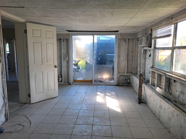 spare room featuring a paneled ceiling, a wall unit AC, and light tile patterned floors