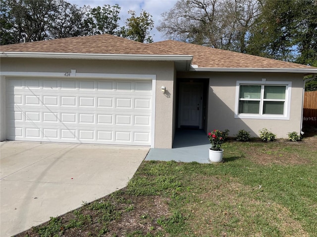 single story home with an attached garage, a shingled roof, a front yard, and stucco siding