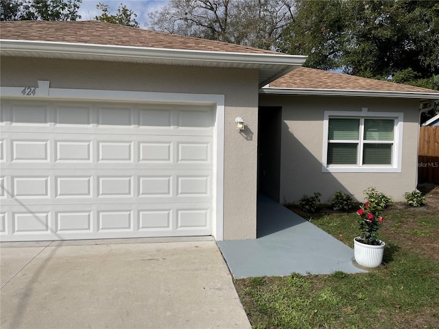 ranch-style home featuring driveway, roof with shingles, an attached garage, and stucco siding