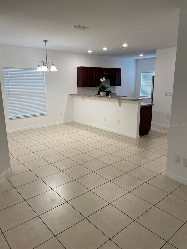 interior space featuring baseboards, a breakfast bar area, a peninsula, light countertops, and recessed lighting