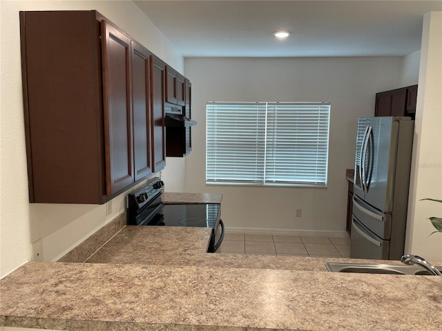 kitchen featuring dark brown cabinetry, freestanding refrigerator, black electric range, under cabinet range hood, and light tile patterned flooring