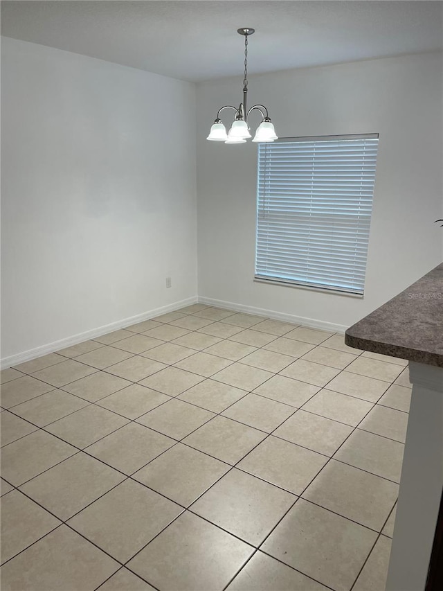 unfurnished dining area featuring baseboards and a notable chandelier