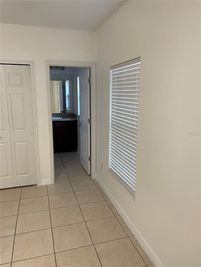 hallway with light tile patterned flooring and baseboards