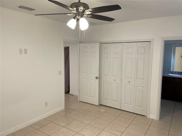 unfurnished bedroom with a closet, light tile patterned flooring, a sink, and visible vents