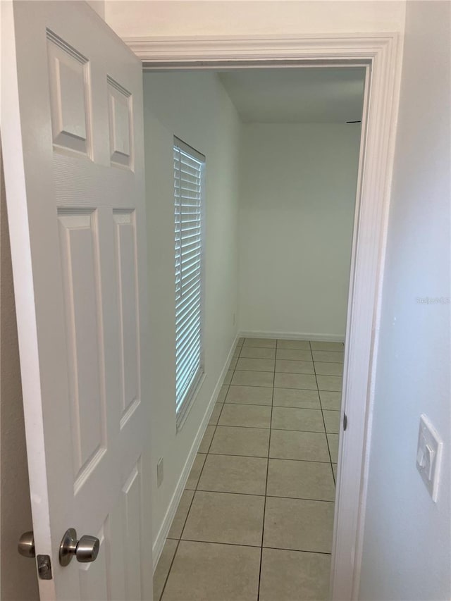 corridor featuring light tile patterned floors and baseboards