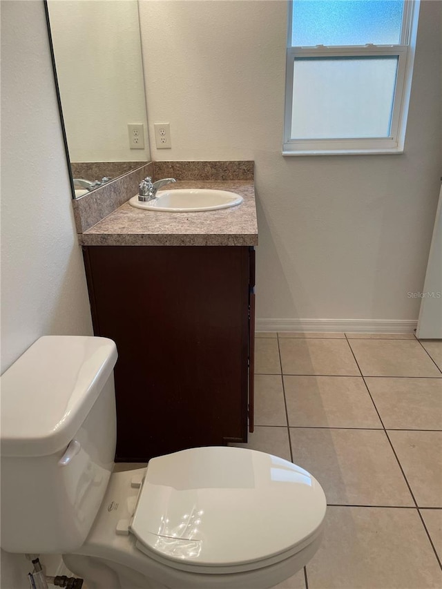 half bath with baseboards, vanity, toilet, and tile patterned floors