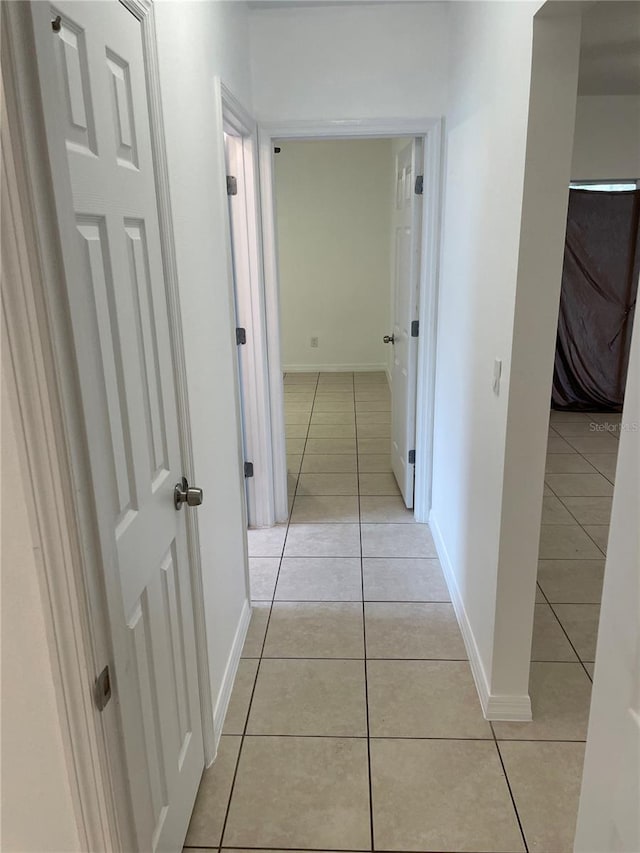 corridor featuring light tile patterned floors and baseboards