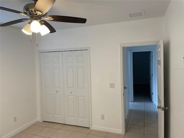 unfurnished bedroom with baseboards, a ceiling fan, a closet, and light tile patterned flooring