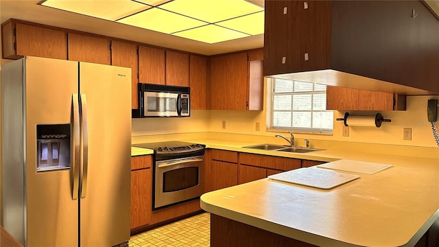 kitchen featuring appliances with stainless steel finishes, brown cabinets, light countertops, and a sink