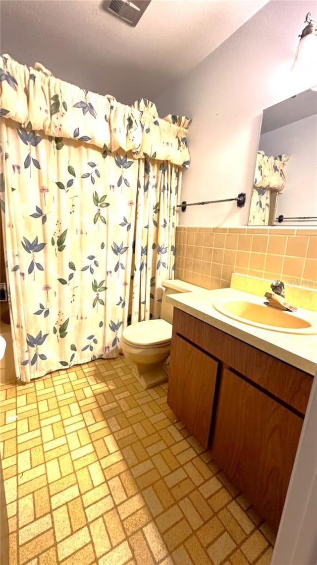 full bath with toilet, visible vents, vanity, tile walls, and a shower with curtain