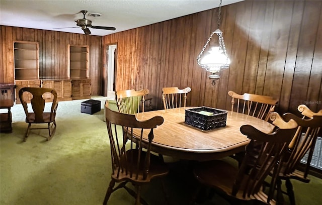 carpeted dining room featuring wood walls, visible vents, and a ceiling fan