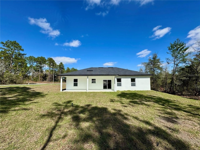 rear view of property featuring a yard and stucco siding