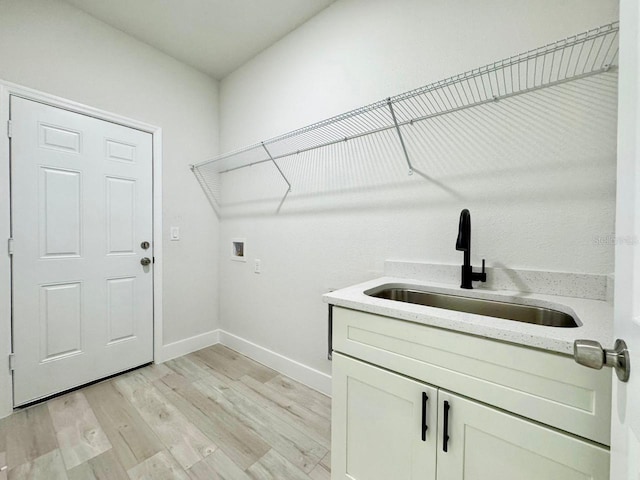 washroom with hookup for a washing machine, baseboards, a sink, and light wood finished floors