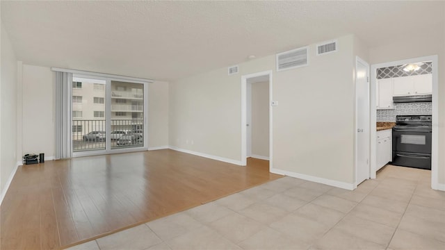 unfurnished room with light wood-type flooring, visible vents, and a textured ceiling