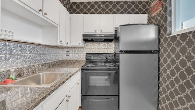 kitchen with a sink, exhaust hood, white cabinets, freestanding refrigerator, and black electric range oven