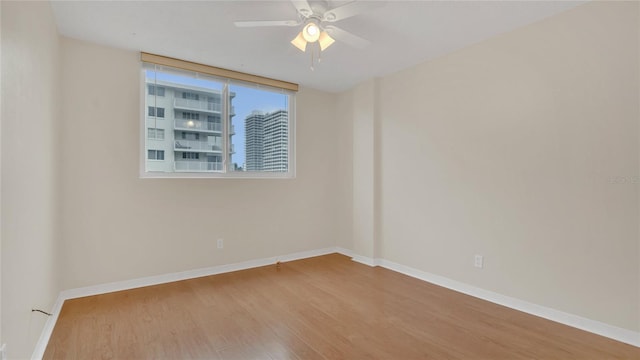 unfurnished room featuring ceiling fan, wood finished floors, and baseboards