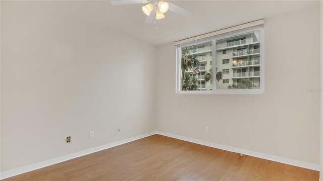 empty room with a ceiling fan, baseboards, and wood finished floors